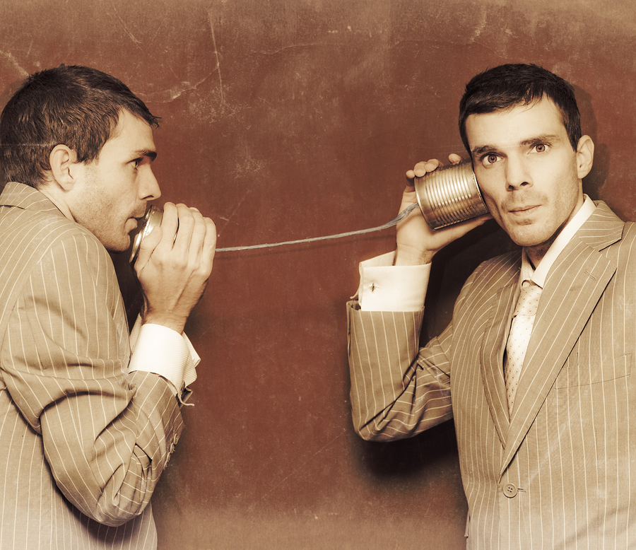 Vintage Photograph Of Two Business People Exchanging Information Down The Line Of A Tin Can Telephone In A Retro Communication Conceptual